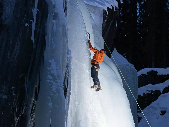 En mann i oransje jakke klatrer is i Hemsedal.