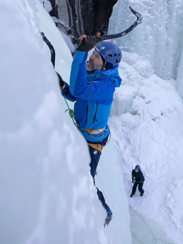 En mann som klatrer is i Hemsedal og en som sikrer han på bakken.