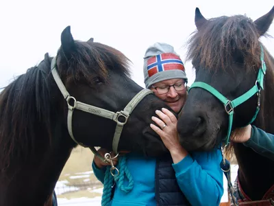 Dame som koser med to hester