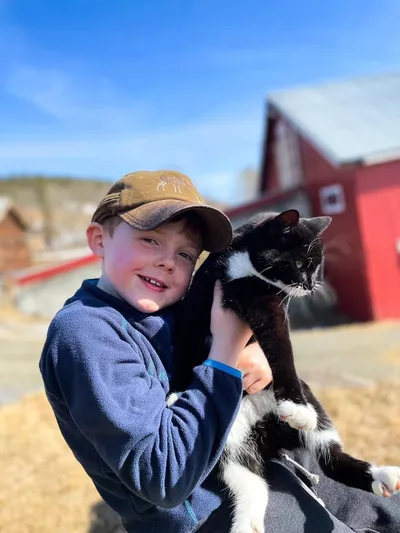 Nærbilde av en gutt som holder en svart-hvit katt