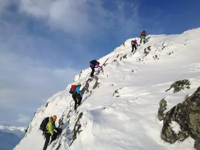 Gruppe mennesker som går på viaferatta på snødekkede fjell.