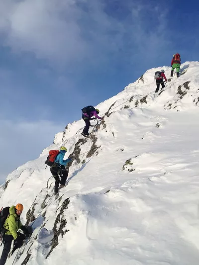 Gruppe mennesker som går på viaferatta på snødekkede fjell.