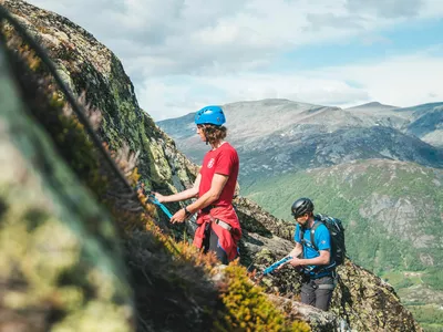 To personer som går oppover fjellet på via ferratta