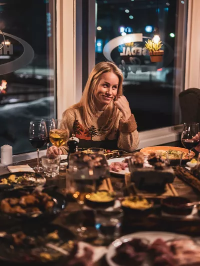 Dame som nyter tapas og vin rundt et bord.