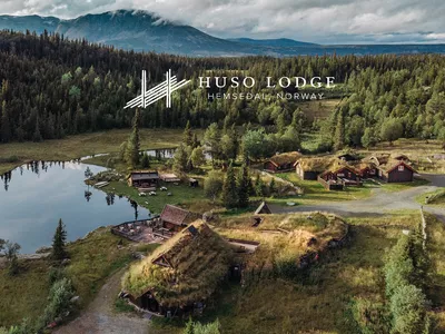 Huso Lodge, logo og bakgrunnsbilde av lodgen i naturen ved et vann.