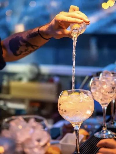 Drikke glass utover en bar benk, og en hånd som lager en og en drink.