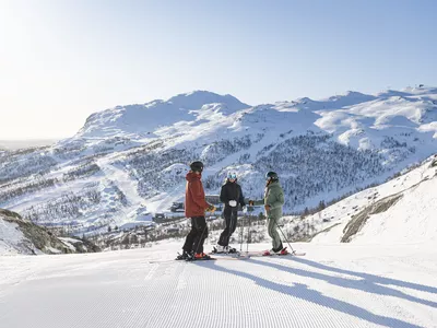 Tre personer står med ski på i skiløypa i SkiStar Hemsedal
