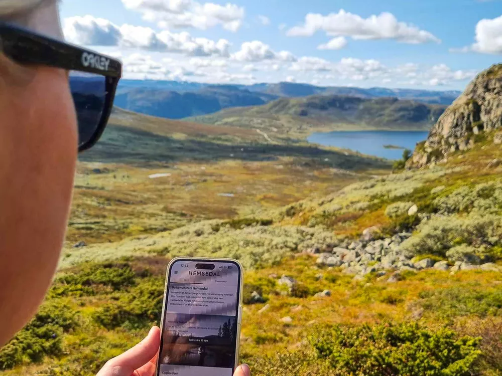 Noen som går tur på fjellet og ser på Hemsedal appen