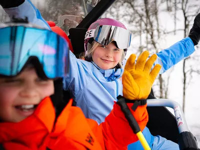 en gutt og en jente som sitter i stolheis i Hemsedal skisenter