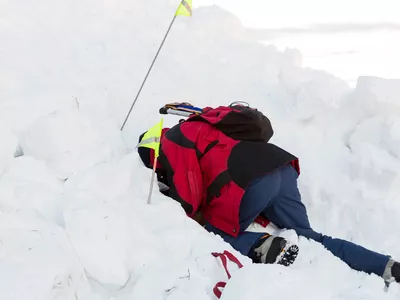 Mann som søker i snø på en skredkurs