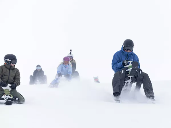 Mann og barn som kjører snowracer ned fjellet i Hemsedal