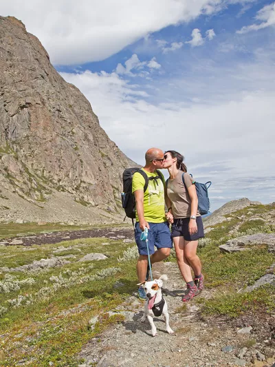 Kyssing i fjellet, hund er også med og fjell i bakgrunnen.
