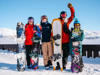 Familie som kjørt snowboard i Hemsedal. De er glade og har hendene i luften